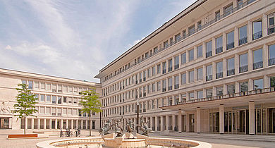 Im Vordergrund ein Brunnen mit Bronzefiguren, im Hintergrund das Gerling Quartier