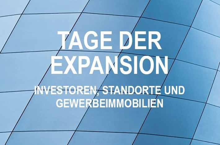 Glaselemente im Hintergrund, darauf weiße Schrift: Tag der Expansion