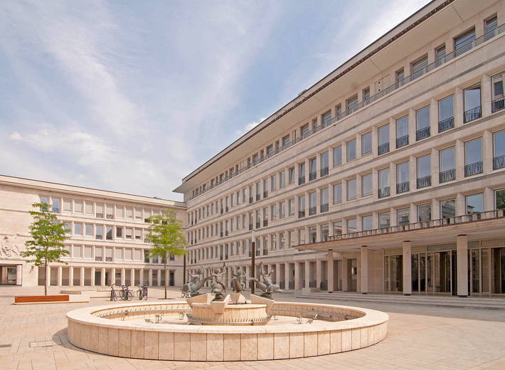 Im Vordergrund ein Brunnen mit Bronzefiguren, im Hintergrund das Gerling Quartier