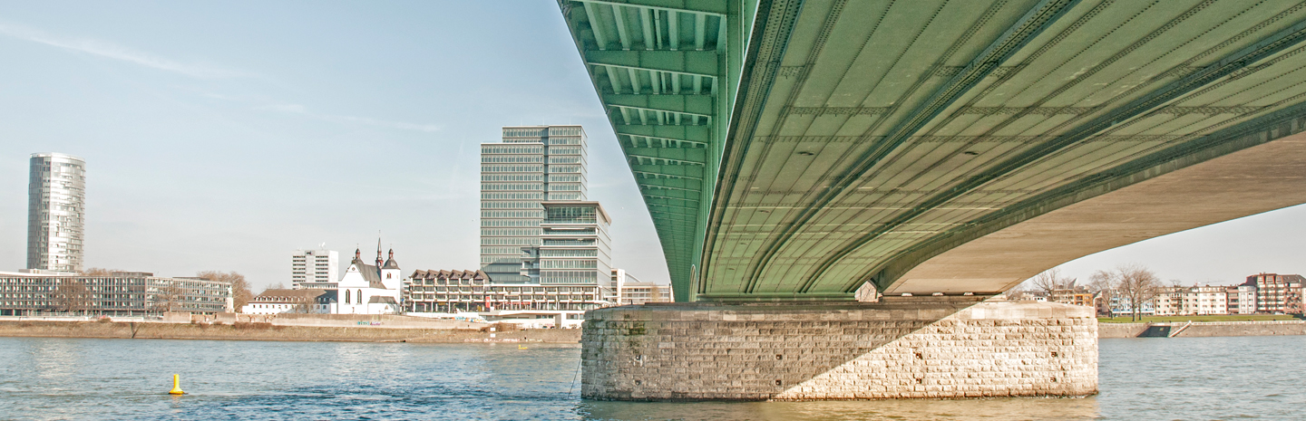 [Translate to Englisch:] Ansicht Deuter Brücke Köln von Unten mit Blick auf Deutz und ein Bürogebäude