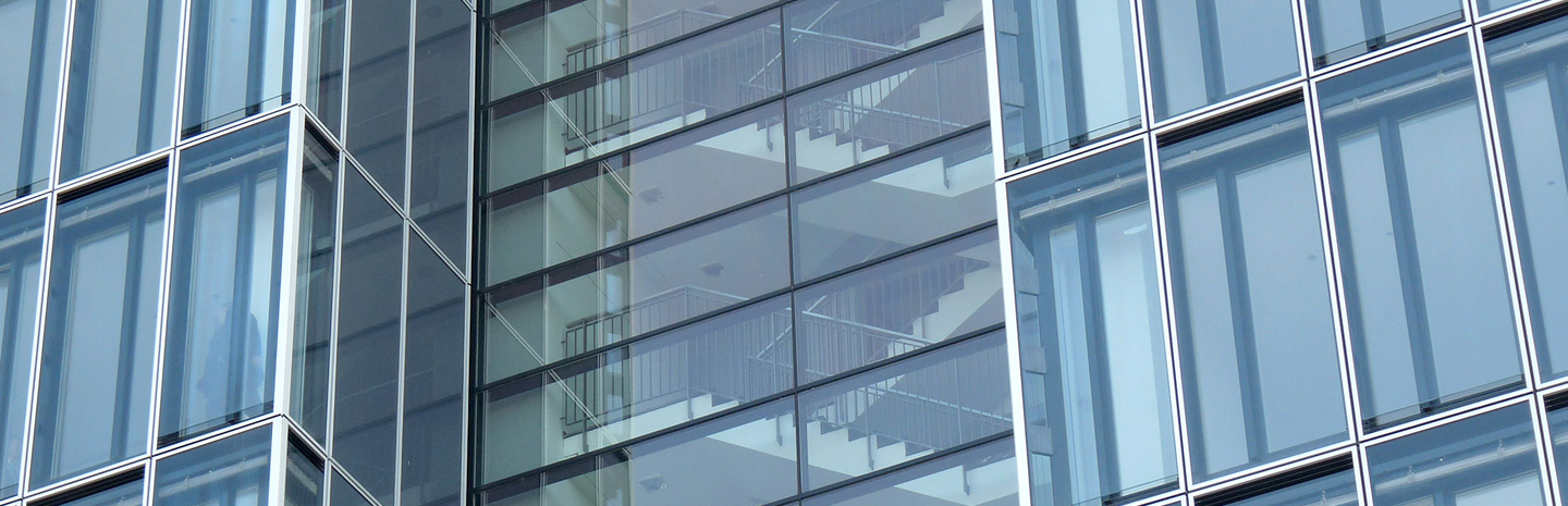 Grundstücke und Restrukturierung: Außenaufnahme eines modernen Gebäudes, Blick durch die Fenster in das Treppenhaus