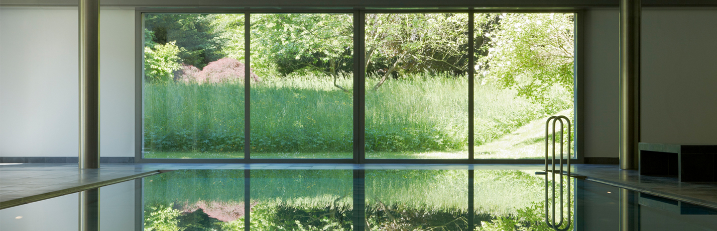 [Translate to Englisch:] Innenansicht Wohnhaus, Schwimmbad mit Blick in den Garten